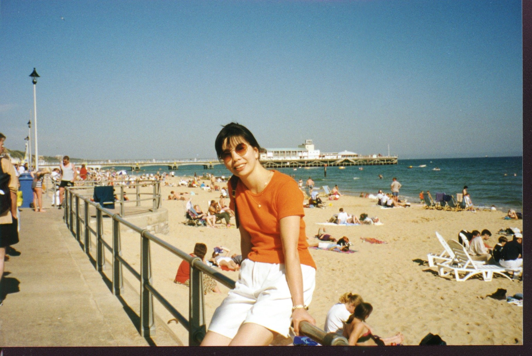 Angela Fong sitting on the metal railing on Bournemouth promenade